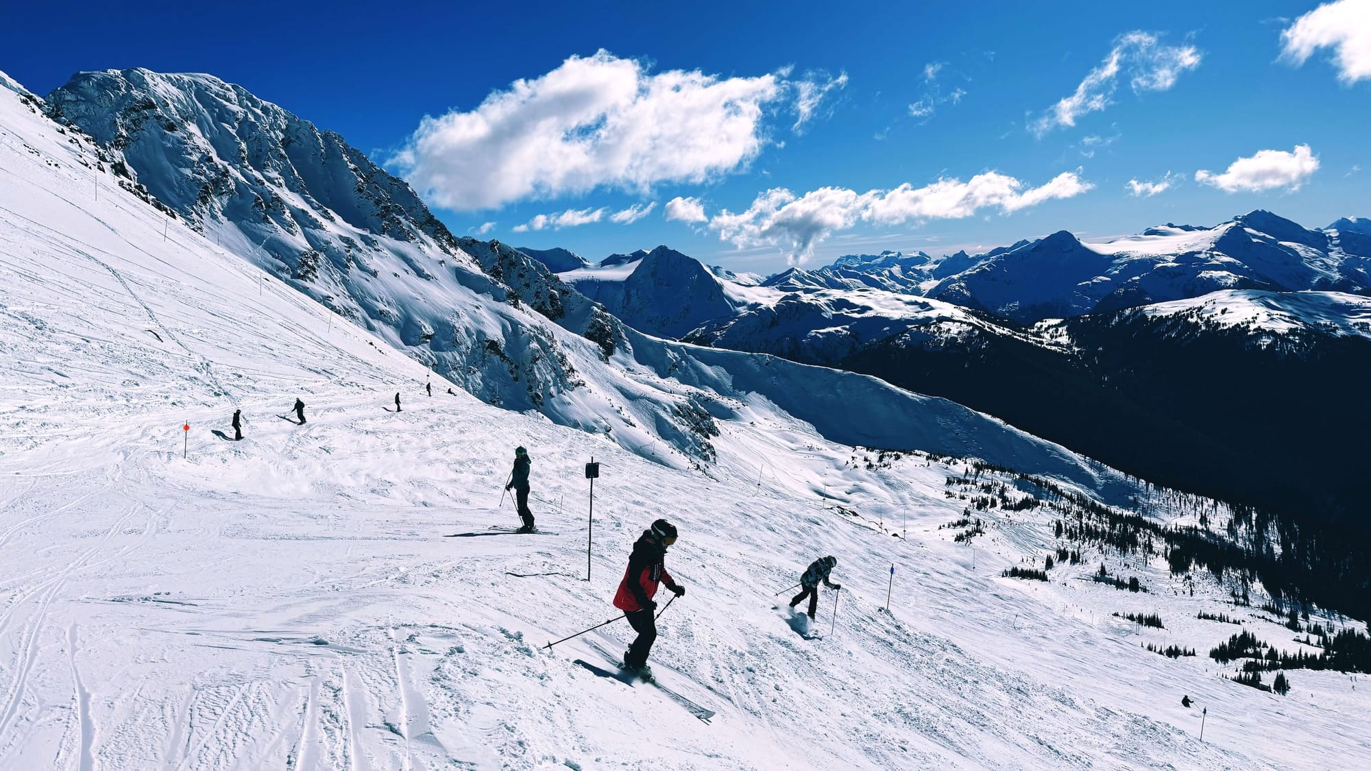 Two skiiers start a run on the side of the mountain.