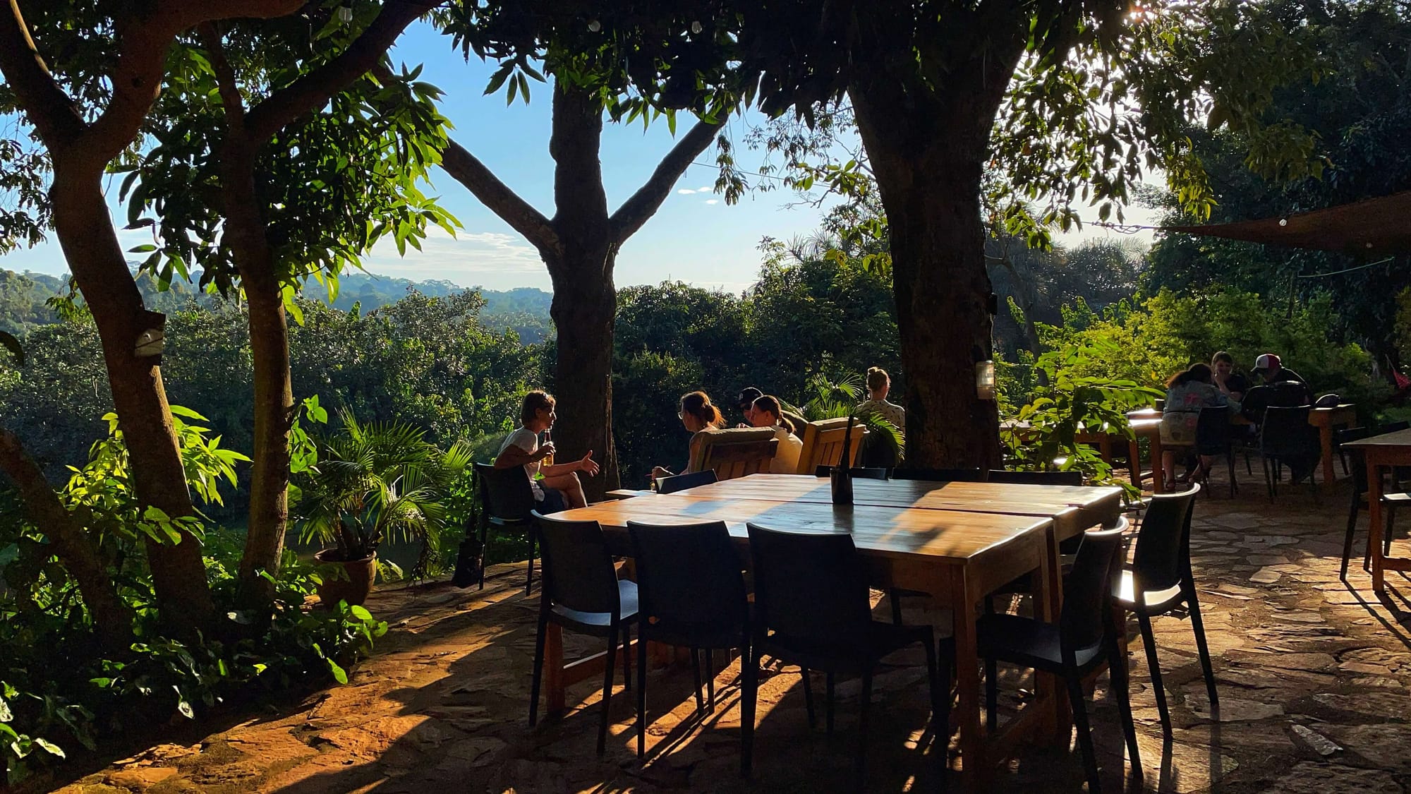 People chatting at the end of the day, with a view of the jungle and trees in the background.